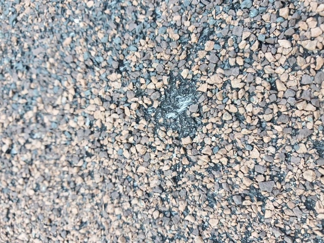 Close-up of hail bruising and granule loss on asphalt shingles
