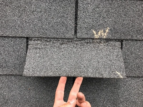 Wind-lifted shingles showing storm damage pattern on a Maryland roof